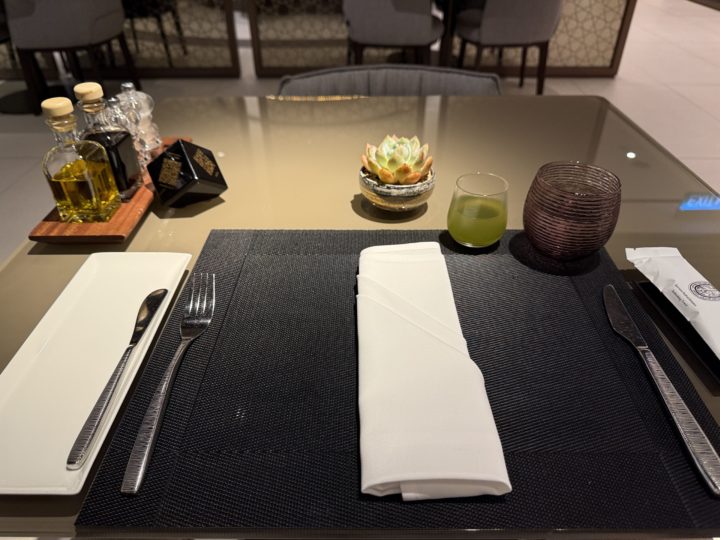 桌面左前方的黑色方塊就是菜單，右手邊的綠色飲料就是迎賓飲